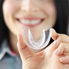 A woman holding up a transparent mouth guard